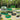 Galvanized raised garden beds in assorted shapes and colors with plants in a garden.