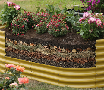 A raised garden bed filled with layered soil and mulch, supporting blooming flowers in an outdoor garden setting.