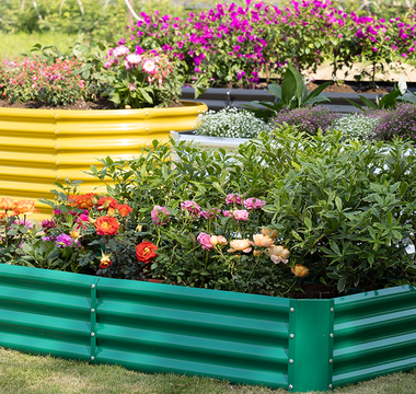 Colorful raised garden beds filled with blooming flowers arranged outdoors on grass.