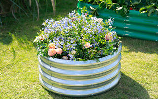 A raised circular garden bed filled with a vibrant mix of colorful flowers.