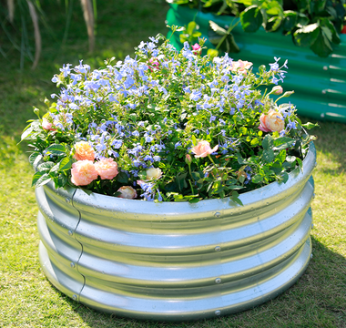 A raised circular garden bed filled with a vibrant mix of colorful flowers.