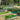Assortment of galvanized raised garden beds in various shapes and colors, filled with healthy plants.